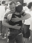 Two men embracing at outdoor gathering by Tom Antonik
